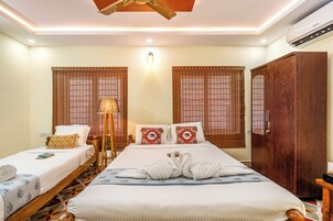 Habitación de hotel con una cama grande, dos mesitas de noche, un armario y un ventilador de techo.