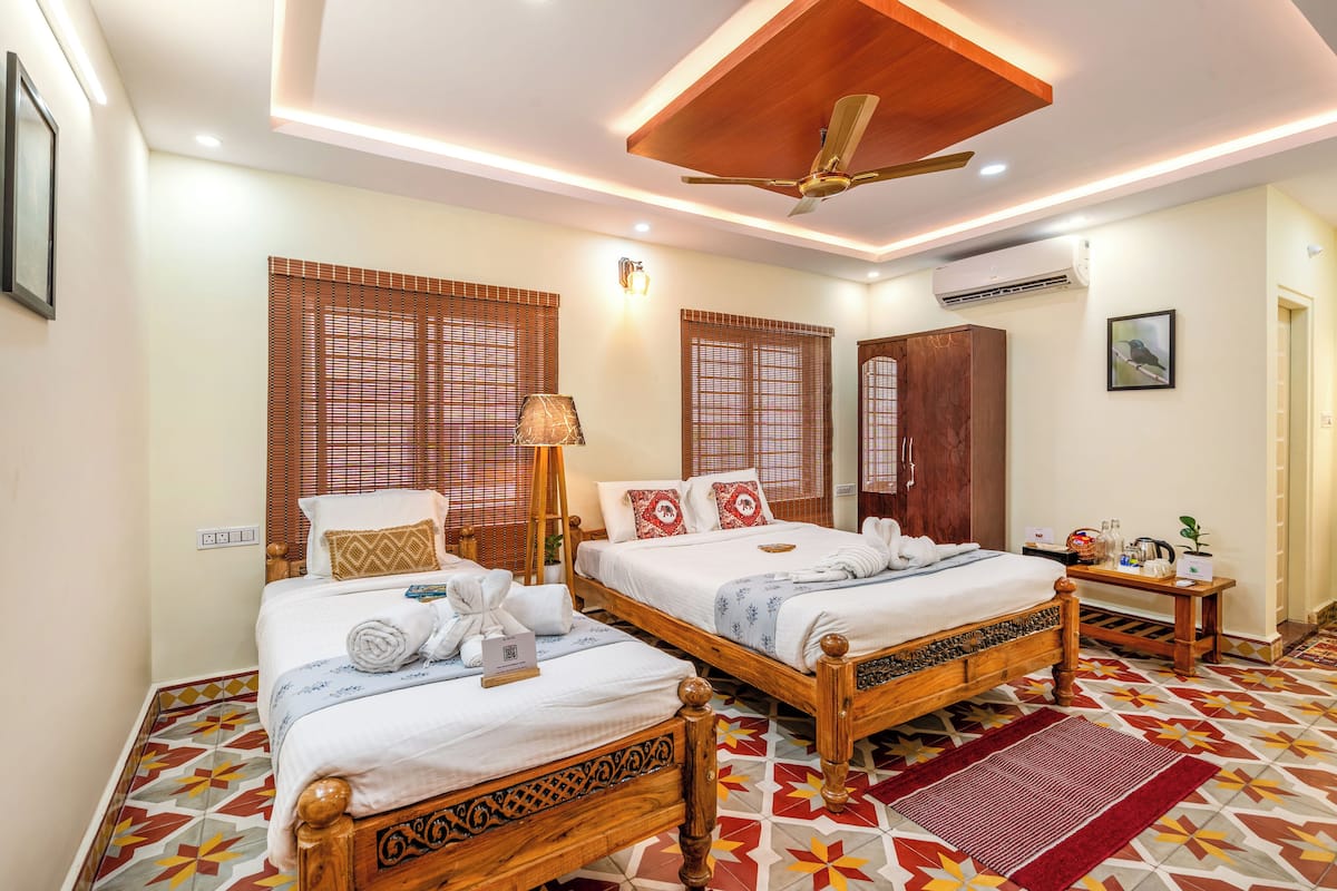 Une chambre d’hôtel avec deux lits en bois, un ventilateur de plafond et un sol à motifs.