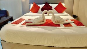 Habitación de hotel con una cama grande, almohadas rojas y blancas, y dos toallas con forma de cisne sobre la cama.