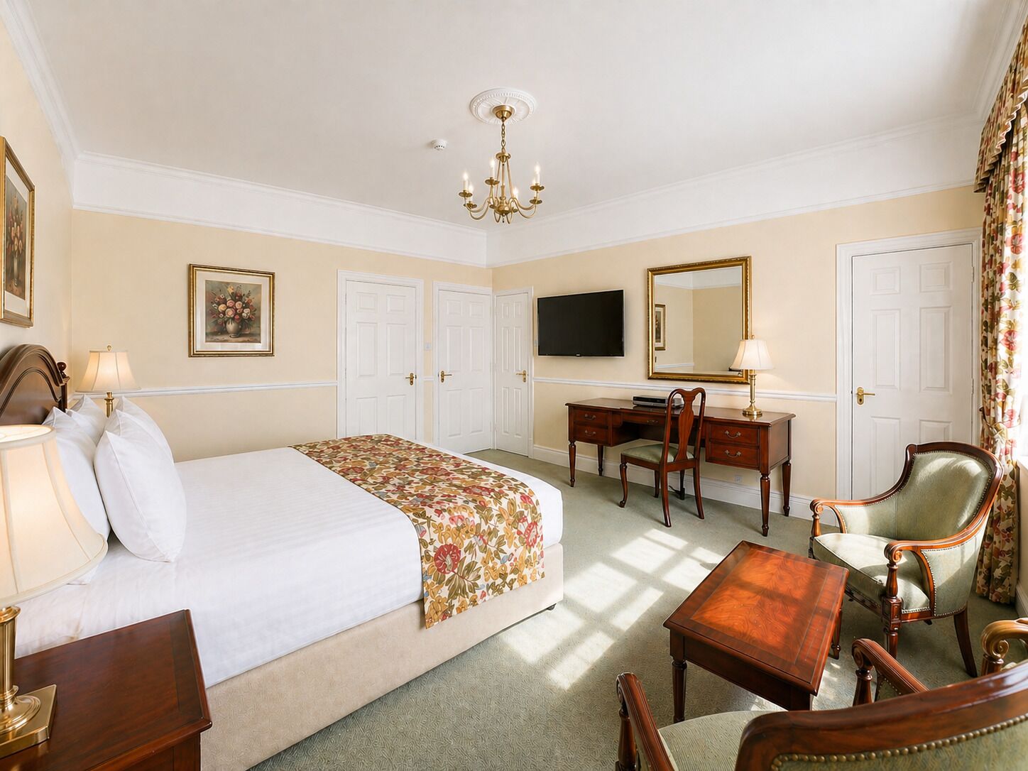 A hotel room with a bed, desk, chair, TV, and a large mirror.