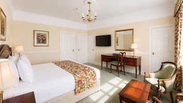 A hotel room with a bed, desk, chair, TV, and a large mirror.