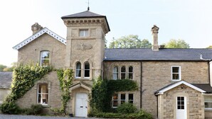 A stone building with a tower, arched windows, and ivy-covered walls. - Nent Hall Country House Hotel (Alston)