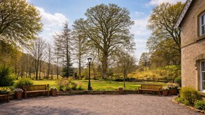 A gravel courtyard with benches, a lamp post, and a building with a window. - Nent Hall Country House Hotel (Alston)