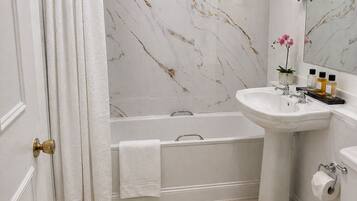 Ein Badezimmer mit einer Badewanne, einem Waschbecken, einer Toilette und einer Marmorwand.
