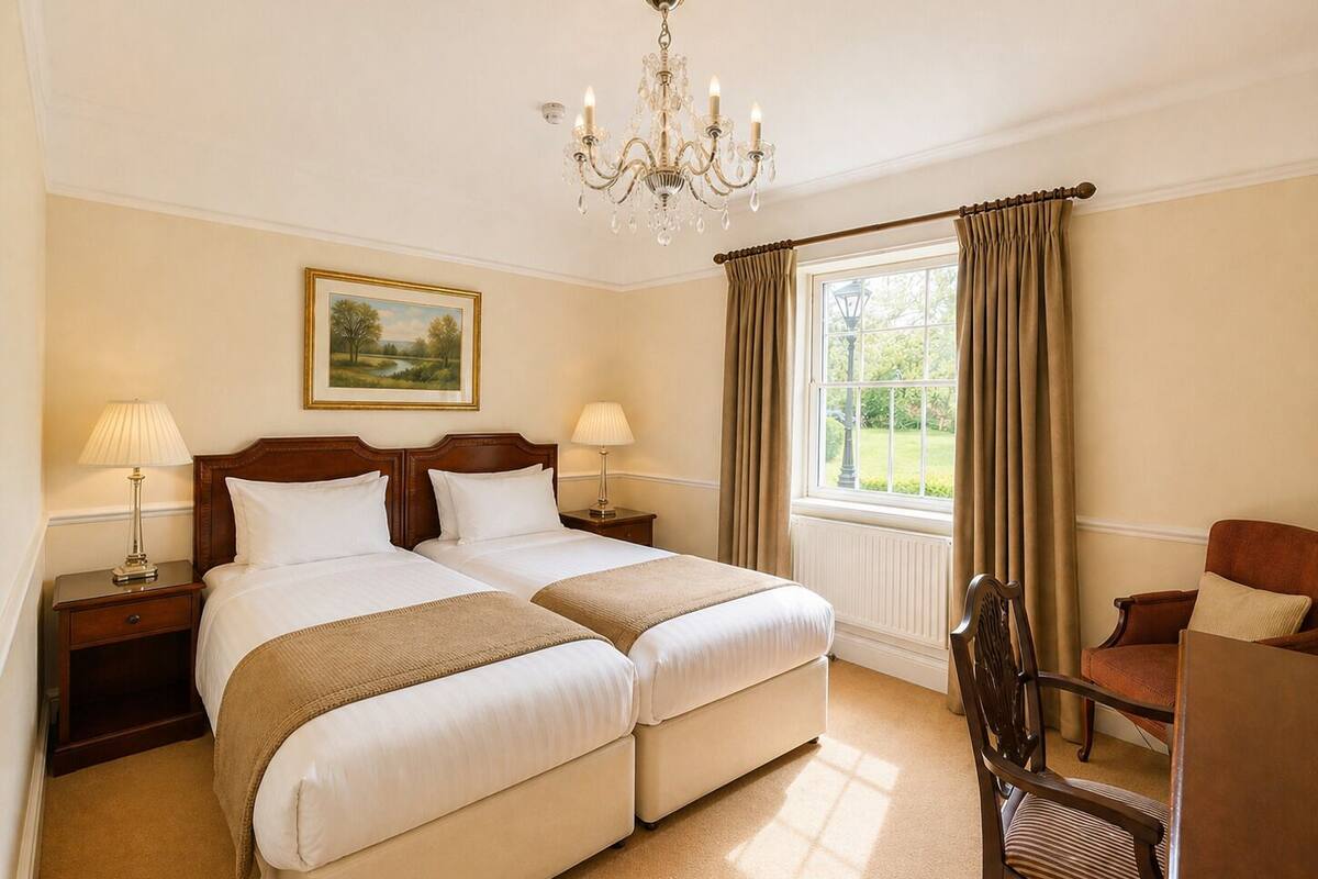 Habitación de hotel con dos camas, un candelabro, un cuadro, una ventana con cortinas y una silla.