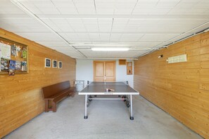 A ping pong table in a room with wooden walls, a bench, and a bulletin board. - Rural Apartment El Corral 1 (Lladurs)