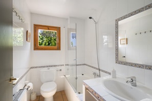 A bathroom with a toilet, a bathtub, a shower, and a sink.