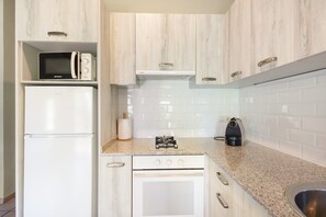 A kitchen with white cabinetry, a microwave, a refrigerator, a stove, and a sink.