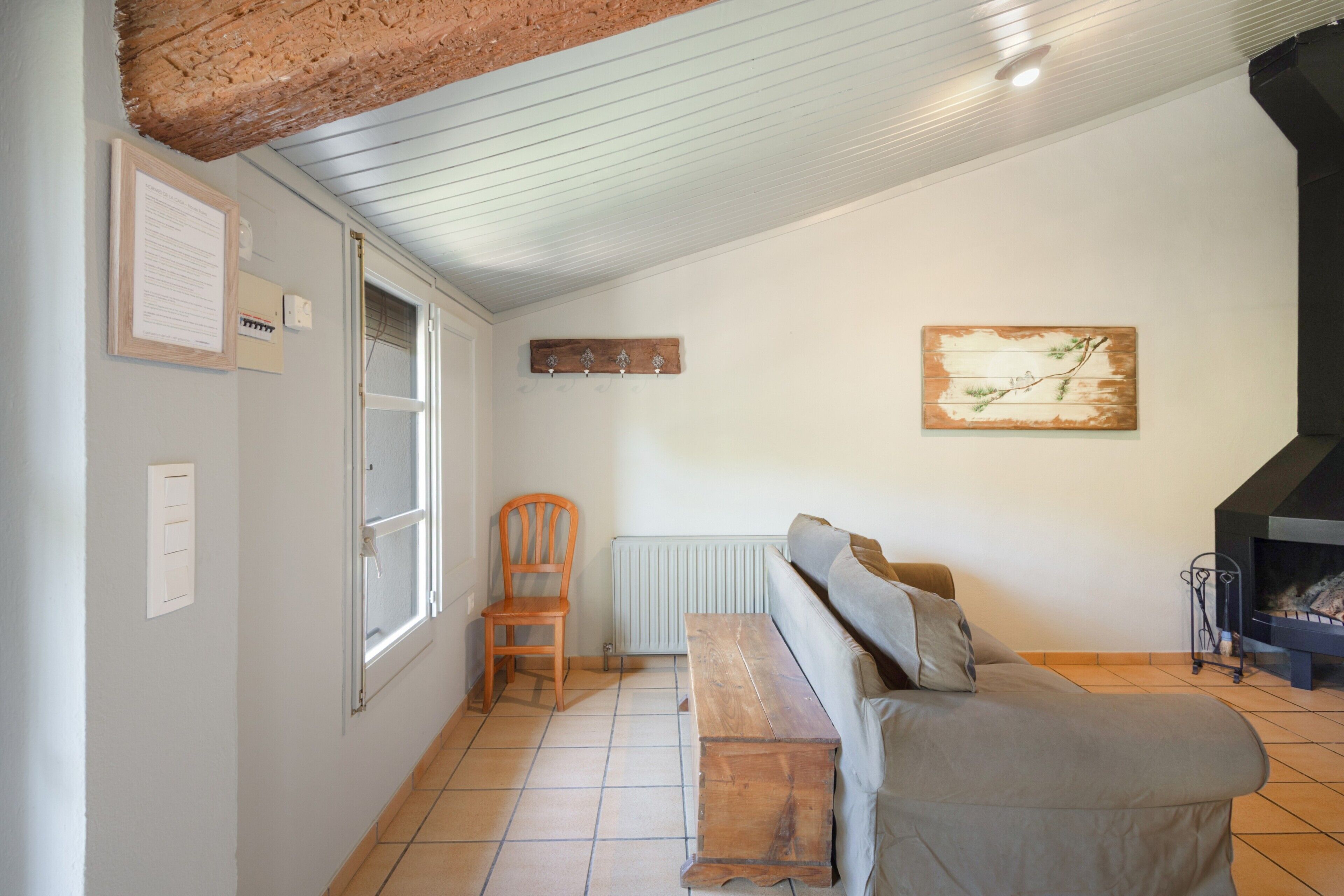 Un salon avec un banc en bois, un canapé, un radiateur, une chemin ée et une fenêtre.