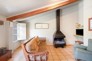 A living room with a wooden ceiling, a sofa, a television, and a fireplace. - Rural Apartment El Corral 2 (Lladurs)