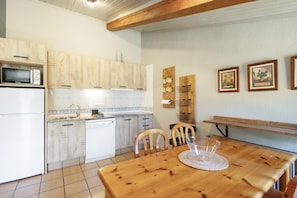 A kitchen with wooden cabinets, a microwave, a dishwasher, and a dining table with chairs. - Rural Apartment El Corral 2 (Lladurs)