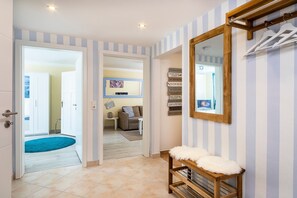 A hallway with a wooden bench, a mirror, and a wall with kitchen rules. - Apartment 'Strandhafer' with Private Terrace, Private Garden and Wi-Fi (Lübeck Travemünde)