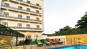A hotel with a swimming pool, outdoor seating, and a multi-story building with balconies. - Huxton Hotel (Lekki)