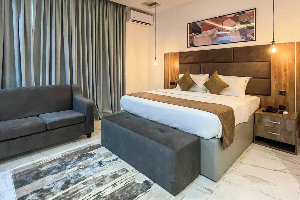 Une chambre d’hôtel moderne avec un grand lit, un canapé, une table basse et un tableau au mur.