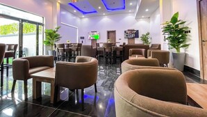 A modern hotel lobby with a seating area, a TV screen, and a ceiling with blue lighting. - Huxton Hotel (Lekki)