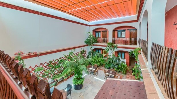A spacious courtyard with a tiled floor, surrounded by wooden railings and potted plants. - Hotel Pozo Rey by youroom (Chipiona)