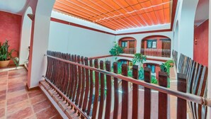 A multi-level interior with a wooden railing, tiled flooring, and a ceiling with a patterned design. - Hotel Pozo Rey by youroom (Chipiona)