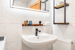A bathroom with a white sink, a mirror, and a towel rack. - Apartment 'Carmen' with Shared Terrace, Private Garden, and Wi-Fi (Wiek)