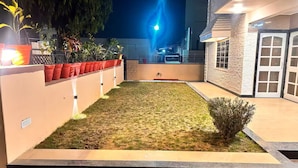 A well-maintained outdoor area with a grassy lawn, potted plants, and a stone wall. - Narpati Villa (Jodhpur)