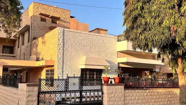 A multi-story residential building with a stone facade, a gated entrance, and a tree in the foreground. - Narpati Villa (Jodhpur)