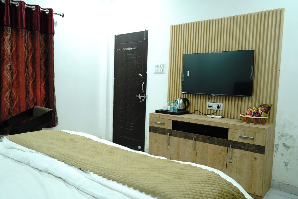 Un dormitorio con cama, televisor montado en una pared de paneles de madera, armario y una puerta con cerradura.