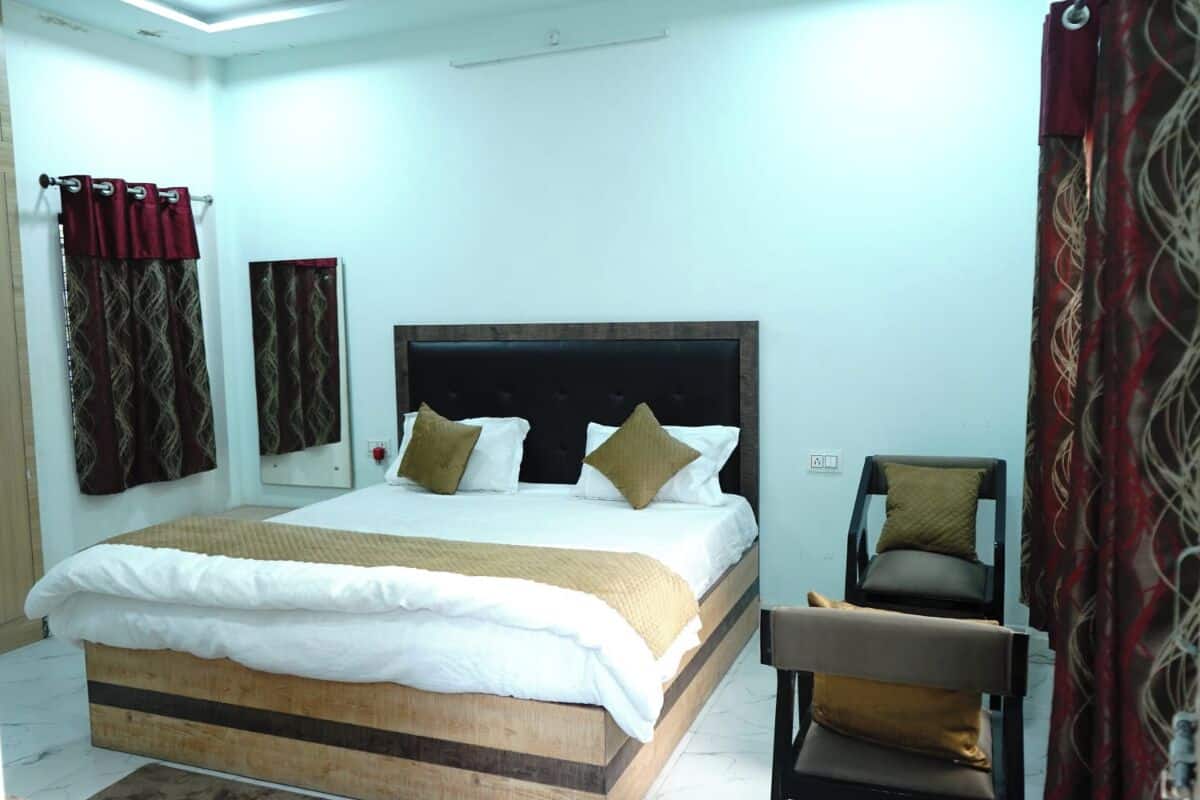 A bedroom with a large bed, a chair, and a mirror.