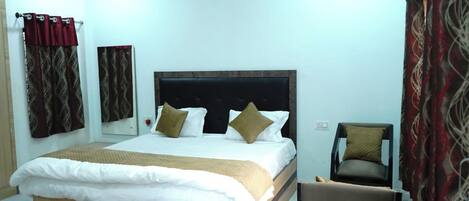 A bedroom with a large bed, a chair, and a mirror.