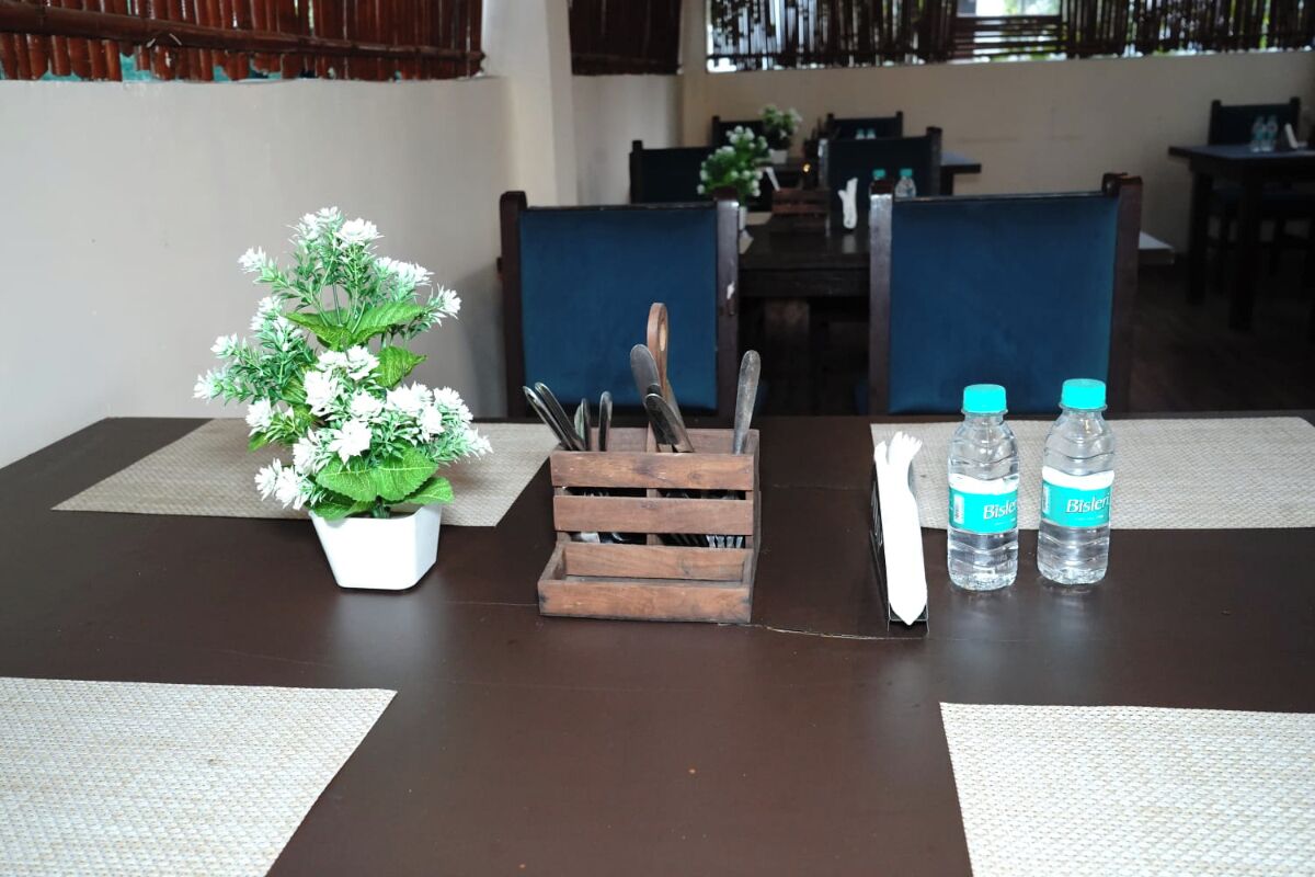 A dining table with a potted plant, a knife block, and two water bottles.