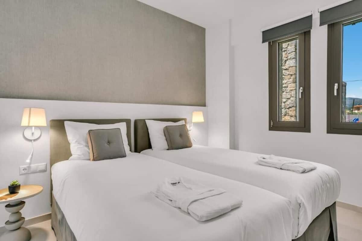 Une chambre d’hôtel avec deux lits, un mur en pierre et une fenêtre donnant sur un paysage agréable.