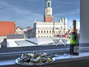 Una botella de champán Moët & Chandon, dos copas de vino y un plato de ostras sobre un alféizar con vistas a un edificio histórico.