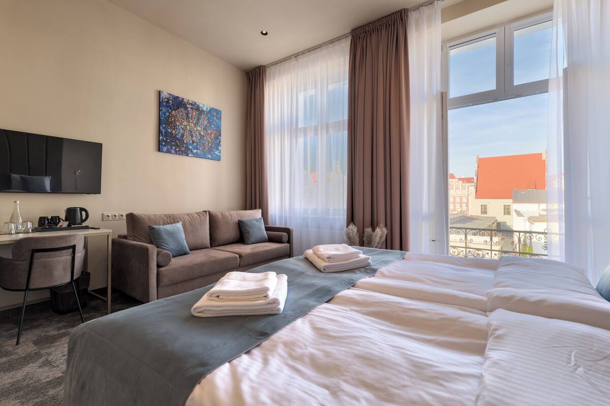 Una habitación de hotel con cama, sofá, escritorio y televisión.