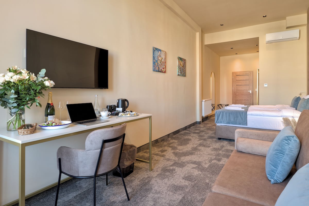 Una habitación de hotel con escritorio, computadora portátil, silla, cama y sofá.