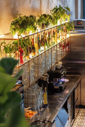 Zona de bar con estantes llenos de vasos, botellas y una máquina para barista.