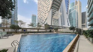 Una piscina con area moderna a bordo vasca, circondata da edifici di grandi dimensioni.