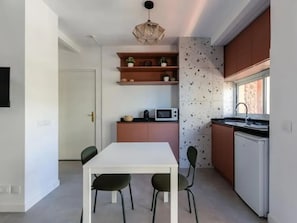 A compact kitchen with a dining area, a microwave, a sink, and a ceiling light fixture. - Patagonia Suite Holiday Apartment with Balcony and Wi-Fi (Puerto de la Cruz)