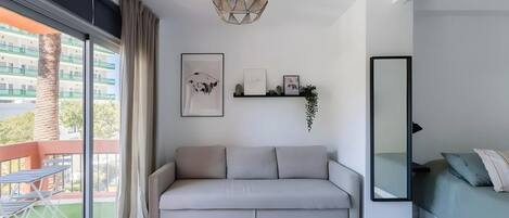 A modern living room with a sofa, a dining table, and a large window.