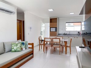 A modern kitchen with white cabinets, a built-in microwave, and a window above the sink. - Residencial Saint Loius (Porto Seguro)