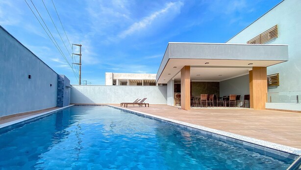 Ein Swimmingpool mit moderner Außensitzgruppe und einem Gebäude mit flachem Dach.