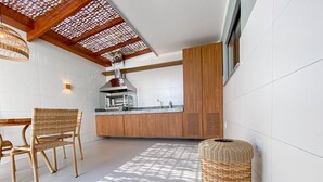 Eine moderne Küche mit Holzausbau, einem eingebauten Herd und einem Essbereich mit Korbstühlen.