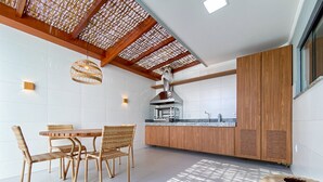 Eine moderne Küche mit Essbereich, mit Holzbalkendecke, weißen Fliesenwänden und einem großen Fenster.