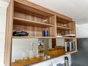 A wooden shelving unit with a glass front, a microwave, and a coffee maker. - Residencial Saint Loius (Porto Seguro)