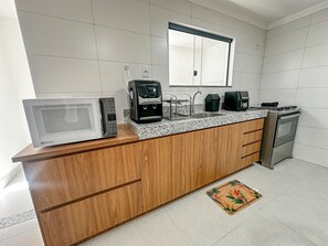 A kitchen with a microwave, coffee maker, and stove. - Residencial Saint Loius (Porto Seguro)
