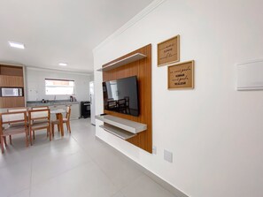 A modern kitchen with a built-in TV, wooden paneling, and two motivational wall art pieces. - Residencial Saint Loius (Porto Seguro)