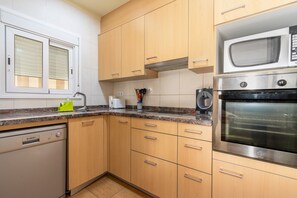 A kitchen with wooden cabinets, a dishwasher, a microwave, and a stove.