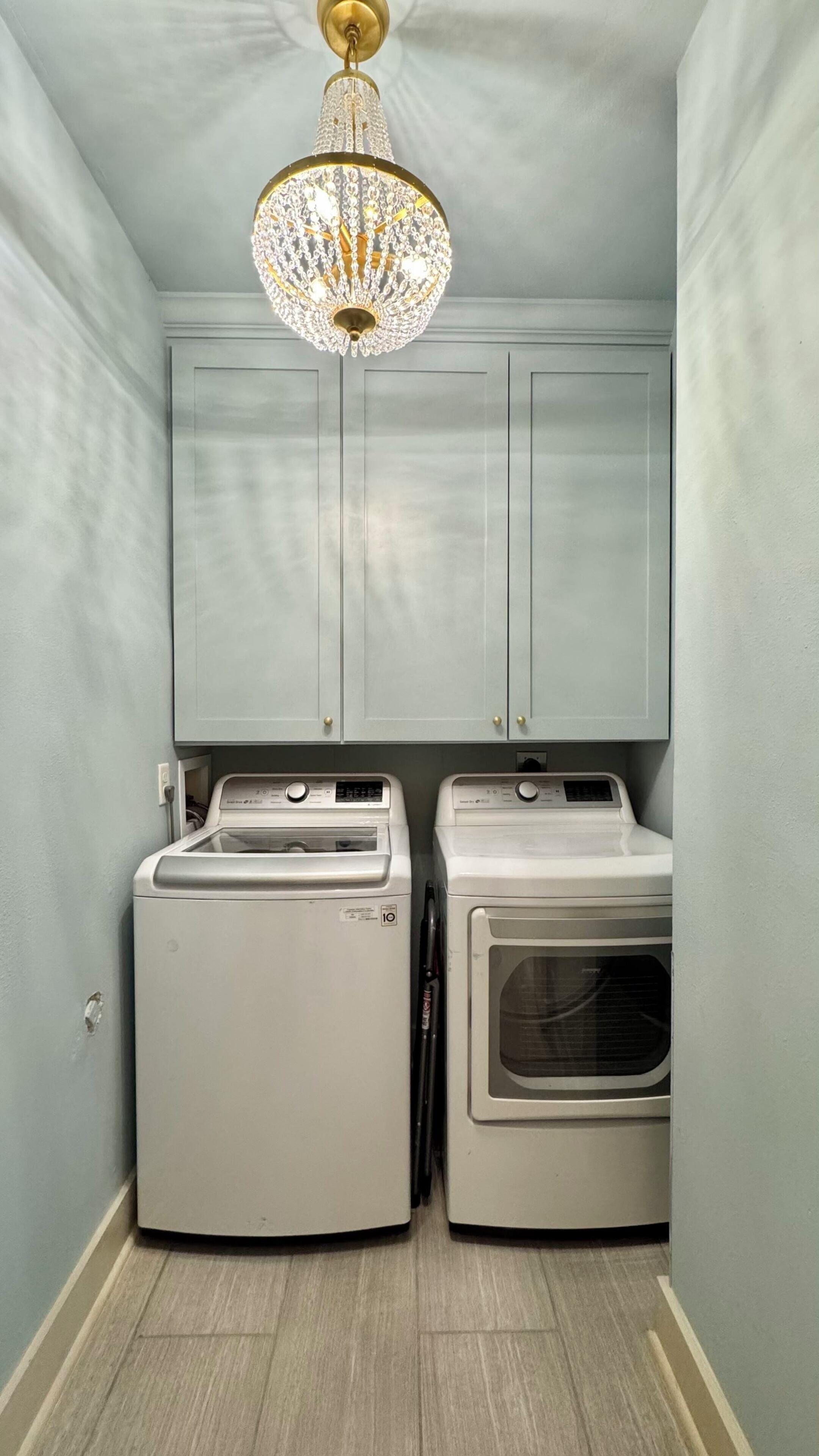 Une buanderie équipée de deux machines à laver, d’un sèche-linge et d’un lustre.