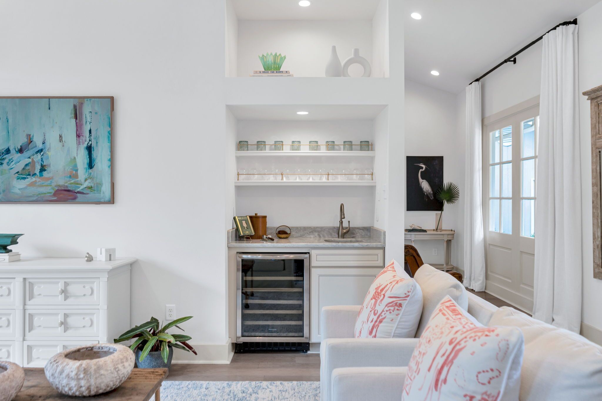 Un salon moderne avec un canapé blanc, un petit coin cuisine et une table à manger.