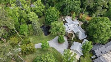 An aerial view of a residential area with multiple houses, a pond, and a well-maintained lawn.