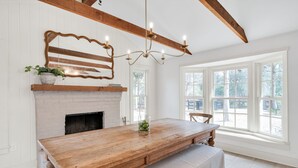Un vaste espace dédié à la salle à manger, avec une table en bois, une cheminée et de grandes fenêtres.