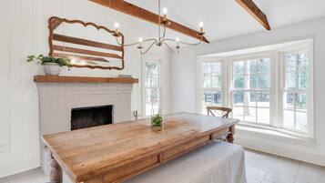 Un vaste espace dédié à la salle à manger, avec une table en bois, une cheminée et de grandes fenêtres.