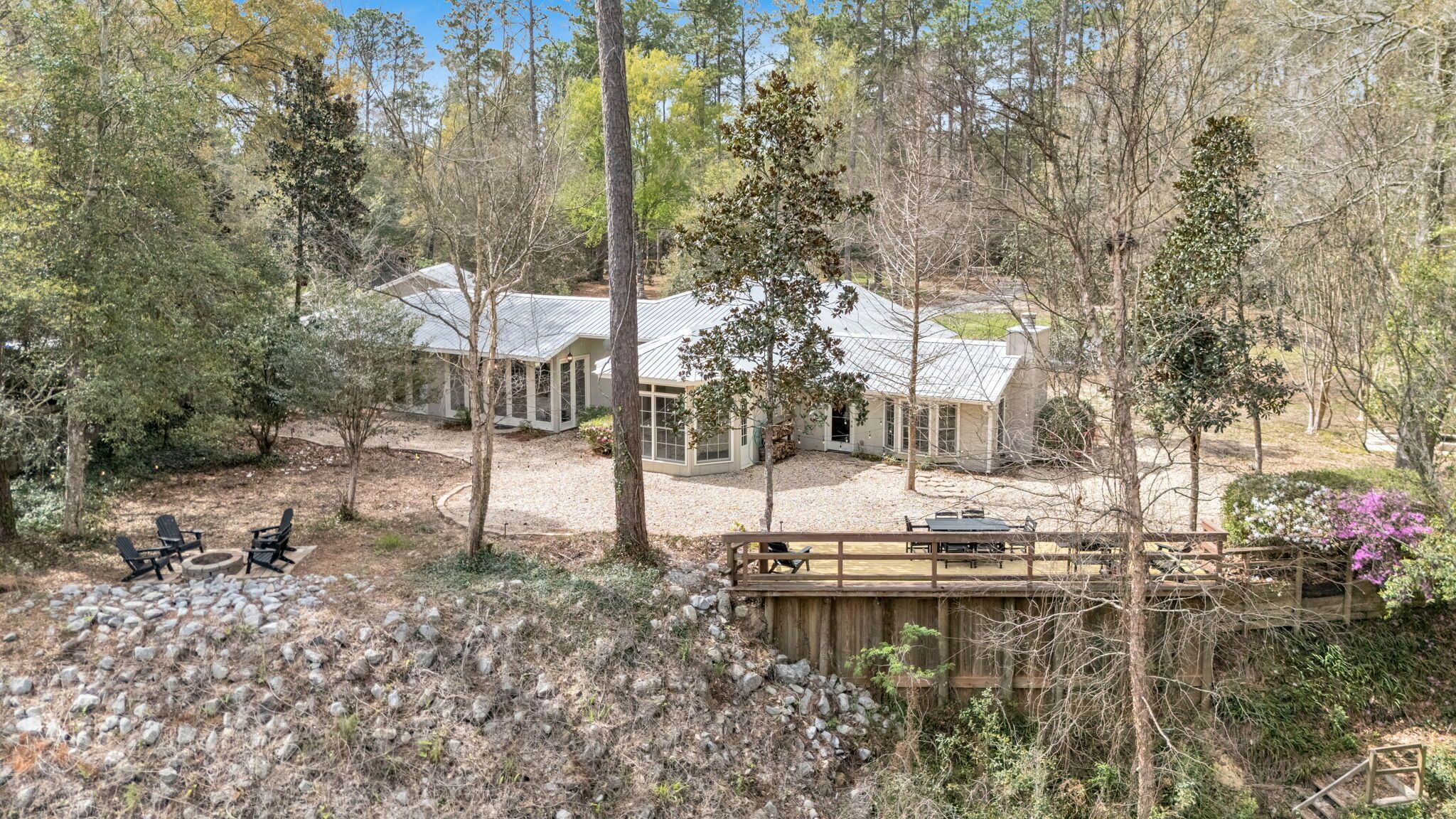 A secluded cabin with a covered patio, surrounded by trees and a small stream.